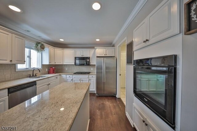 kitchen with black appliances, a sink, crown molding, light stone countertops, and backsplash