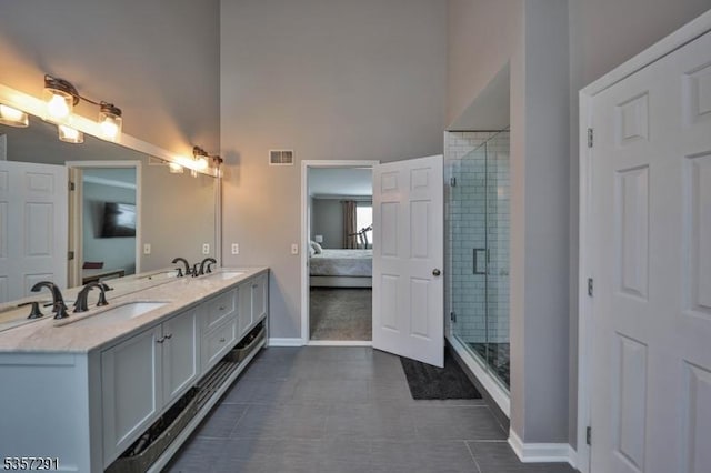 ensuite bathroom featuring baseboards, double vanity, a shower stall, tile patterned floors, and a towering ceiling