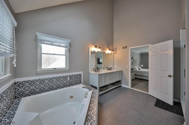 bathroom featuring high vaulted ceiling, a jetted tub, vanity, ensuite bath, and baseboards