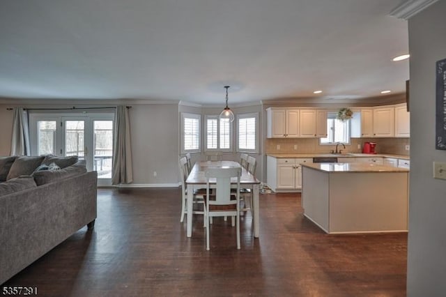 kitchen featuring crown molding, light countertops, dark wood-style floors, backsplash, and open floor plan