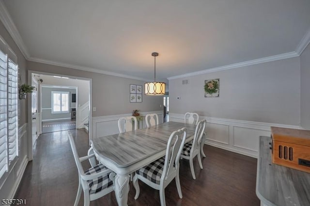 dining room featuring ornamental molding, dark wood-type flooring, and wainscoting