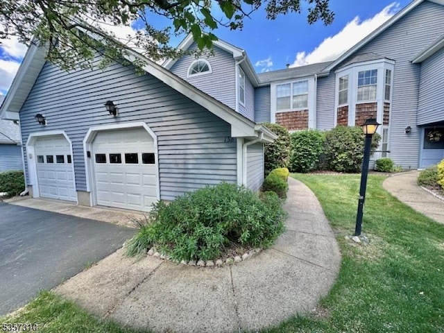 view of home's exterior featuring asphalt driveway, an attached garage, and a yard