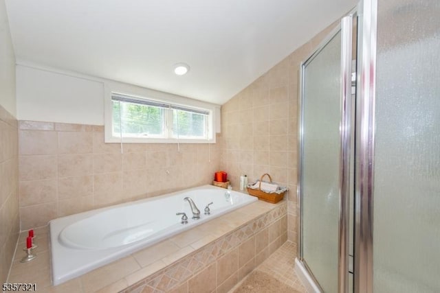 bathroom featuring tile walls, a stall shower, and a garden tub