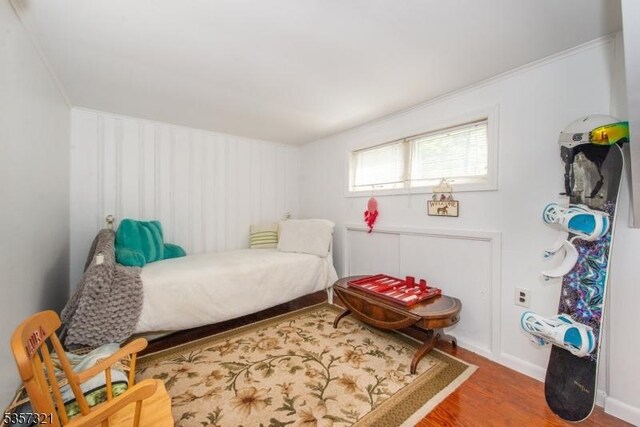 bedroom featuring wood finished floors and ornamental molding