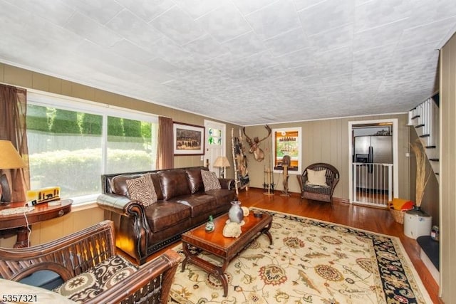 living room with healthy amount of natural light, wood finished floors, and stairs