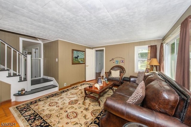living area with wood finished floors, crown molding, and stairway