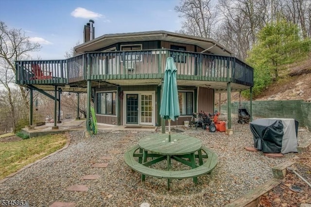 rear view of property with a wooden deck, a chimney, and a patio area