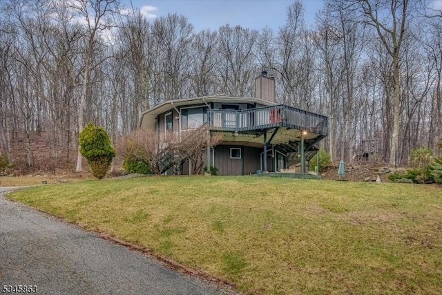 view of front facade with stairs, a wooden deck, a front lawn, and a chimney