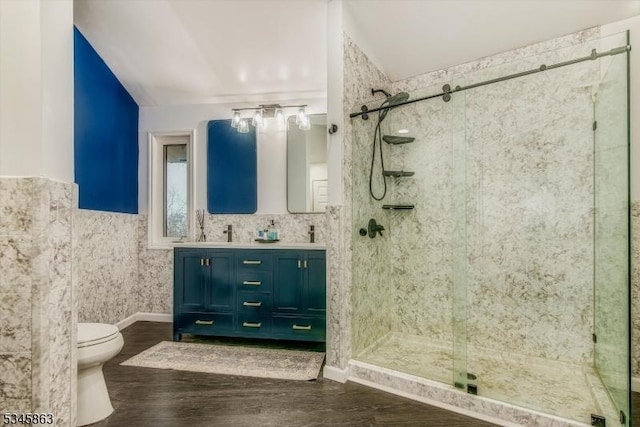 bathroom featuring toilet, a stall shower, double vanity, wood finished floors, and lofted ceiling