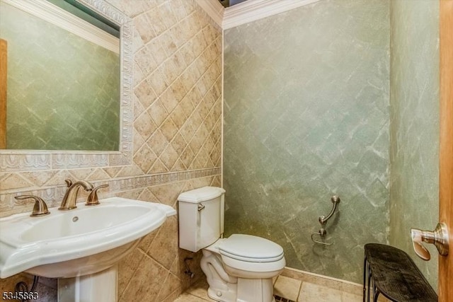 half bathroom with toilet, a sink, tile patterned floors, and crown molding