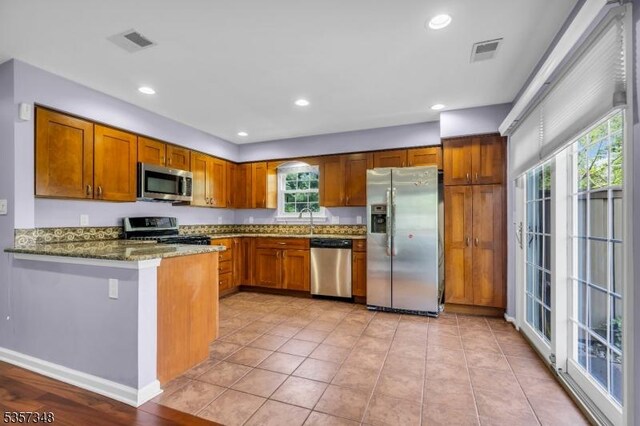 1901 Stech Dr, Bridgewater Twp, NJ 08807 - kitchen featuring appliances with stainless steel finishes, dark stone countertops, brown cabinets, recessed lighting, and a peninsula