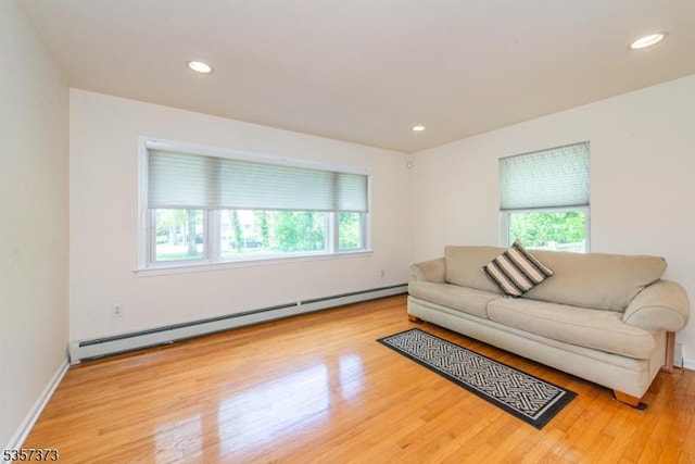 living area with baseboard heating, plenty of natural light, wood finished floors, recessed lighting, and baseboards