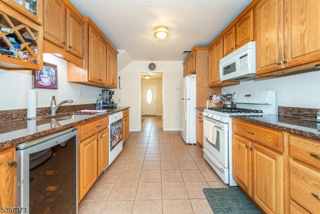 kitchen featuring white appliances, wine cooler, light tile patterned floors, dark stone countertops, and brown cabinets