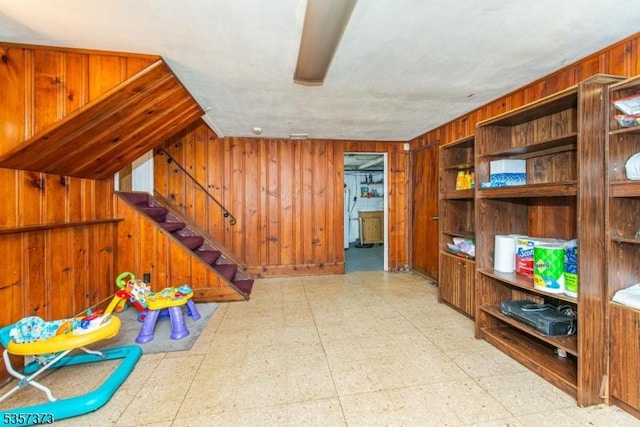 rec room with light flooring and wood walls