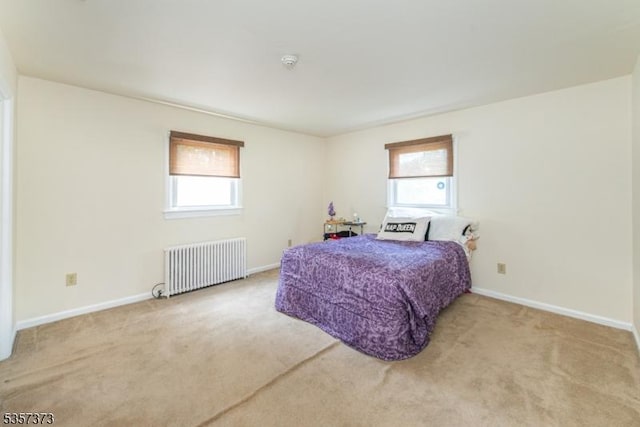 bedroom with radiator heating unit, multiple windows, and carpet flooring