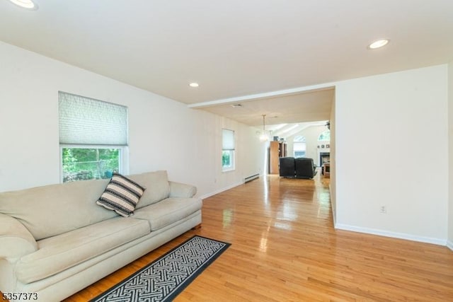 living room featuring healthy amount of natural light, light wood finished floors, baseboard heating, baseboards, and recessed lighting