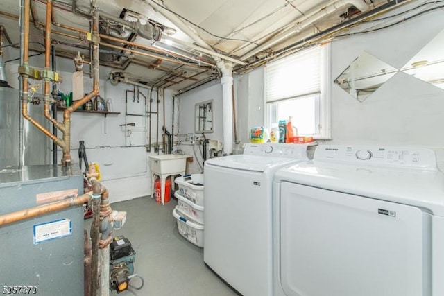 clothes washing area with separate washer and dryer, a heating unit, and a sink