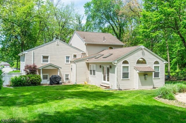 back of property featuring a lawn and a shingled roof