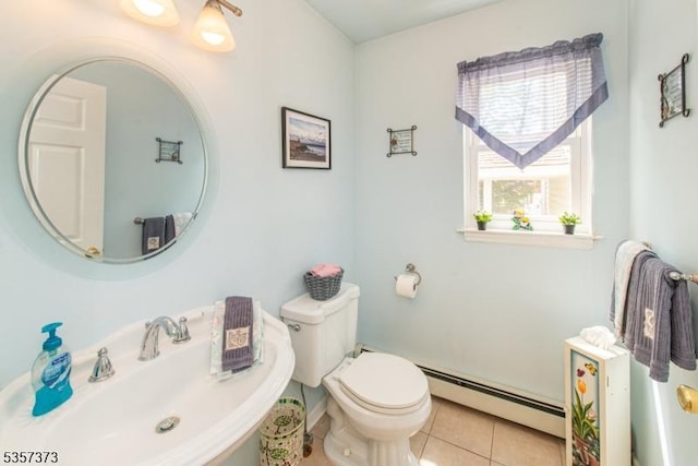 half bath with a baseboard radiator, a sink, tile patterned flooring, and toilet
