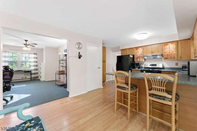 39 Circle Dr, Rockaway Twp, NJ 07866 - kitchen featuring stainless steel range with gas stovetop, under cabinet range hood, freestanding refrigerator, a peninsula, and dark countertops