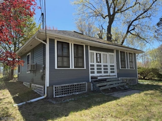 view of side of home with entry steps, a lawn, and cooling unit
