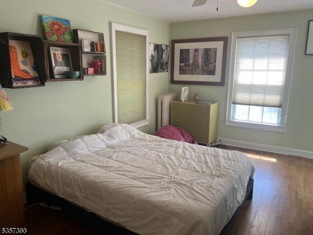 bedroom featuring wood-type flooring, radiator, baseboards, and ceiling fan
