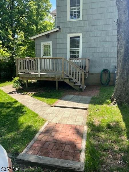 rear view of house featuring a deck and a lawn