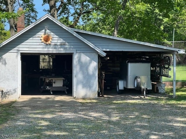 view of outdoor structure with driveway, an outbuilding, and fence