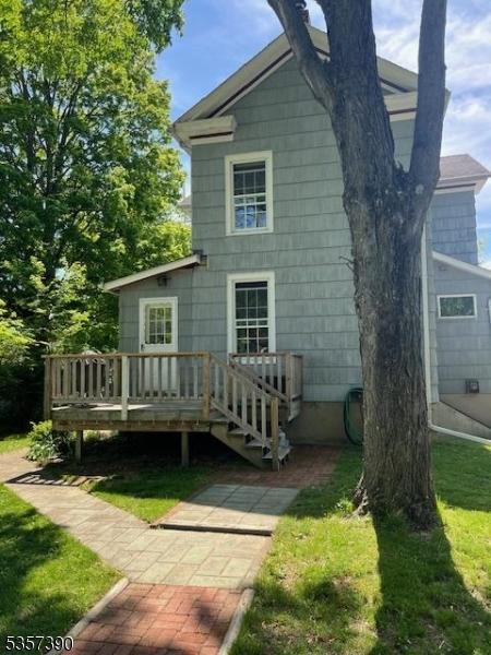 back of property featuring a wooden deck and a yard