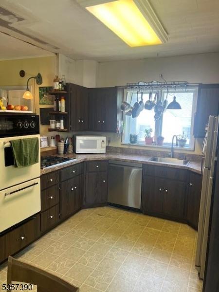 kitchen featuring stainless steel appliances, a sink, a warming drawer, and dark brown cabinets