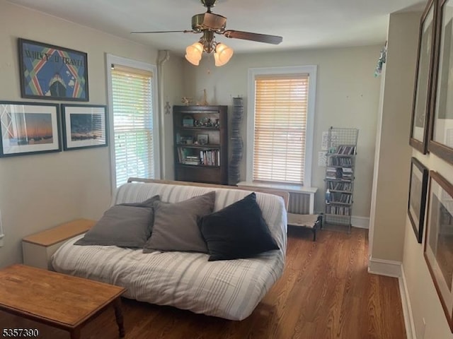 living area with a ceiling fan, wood finished floors, and baseboards