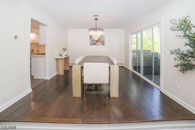 dining area with dark wood-type flooring, a chandelier, baseboards, and baseboard heating