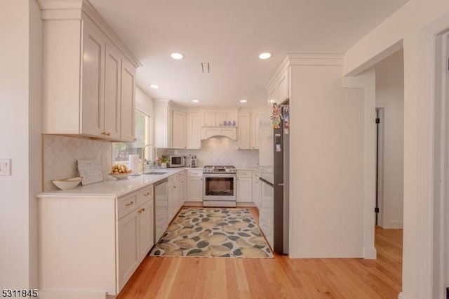 24 Covered Bridge Rd, Branchburg Twp, NJ 08853 - kitchen featuring appliances with stainless steel finishes, light wood finished floors, light countertops, decorative backsplash, and a sink