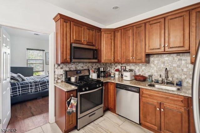 234 Lt Glenn Zamorski Dr, Elizabeth City, NJ 07206 - kitchen featuring appliances with stainless steel finishes, a sink, light stone counters, decorative backsplash, and brown cabinets