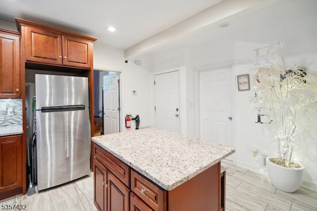 234 Lt Glenn Zamorski Dr, Elizabeth City, NJ 07206 - kitchen featuring freestanding refrigerator, a center island, light stone counters, recessed lighting, and brown cabinets