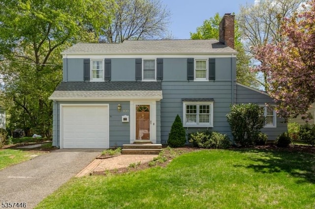 view of front of property featuring a chimney, a front yard, an attached garage, driveway, and a shingled roof