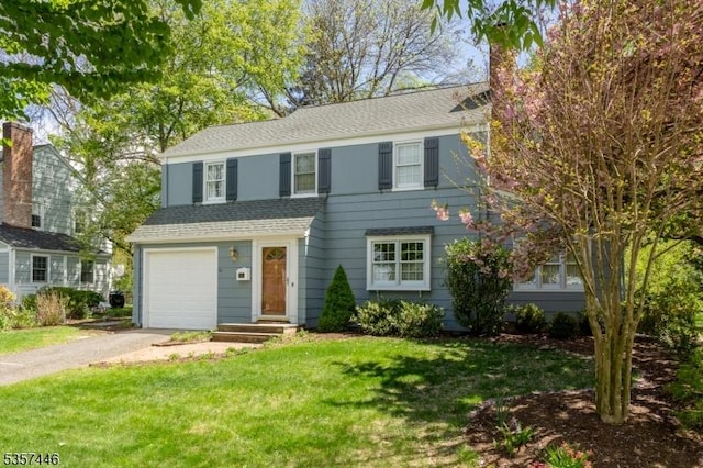 view of front of house featuring asphalt driveway, a chimney, a front lawn, a shingled roof, and a garage