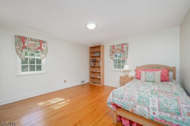 bedroom featuring light wood finished floors and baseboards