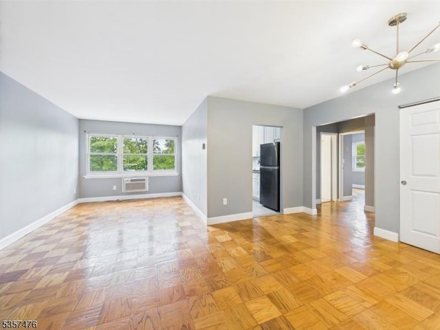 unfurnished living room featuring healthy amount of natural light, a chandelier, a wall mounted AC, and baseboards