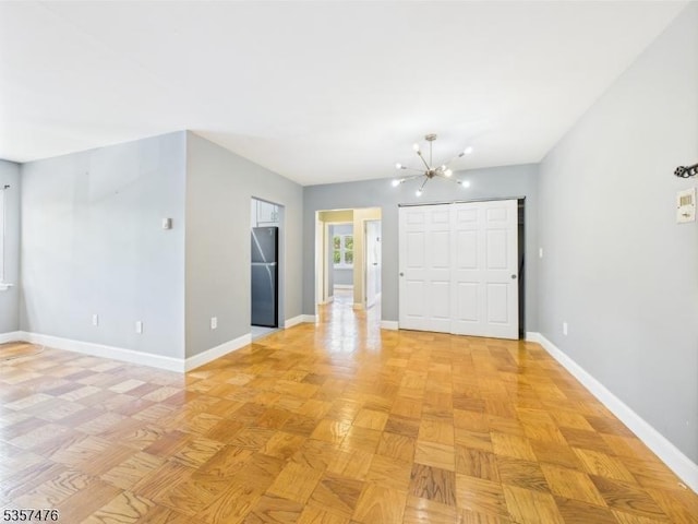 empty room featuring a chandelier and baseboards