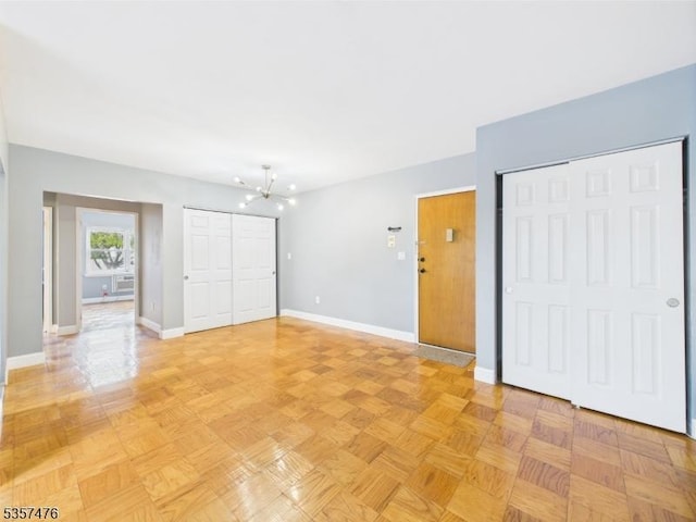 unfurnished bedroom with multiple closets, baseboards, and a chandelier