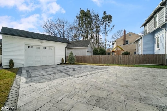 garage featuring driveway and fence