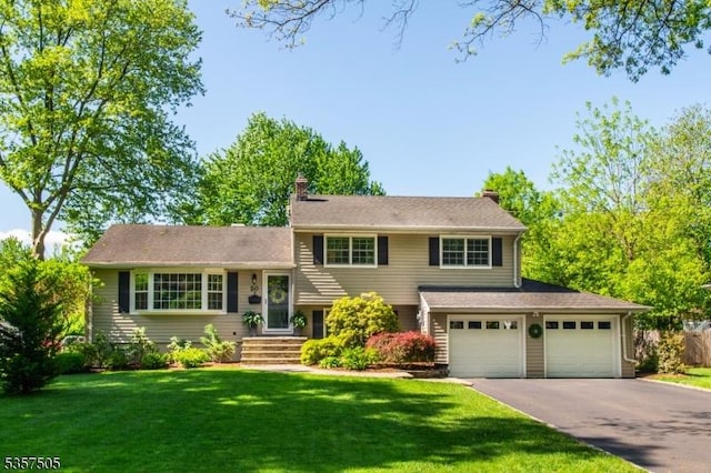 split level home with asphalt driveway, a front yard, and a chimney