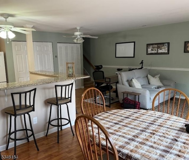 dining space featuring a ceiling fan, wood finished floors, and baseboards