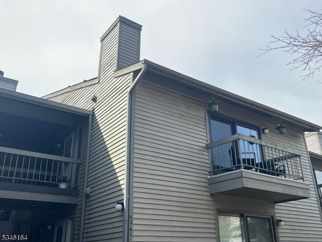 view of side of property featuring a balcony and a chimney