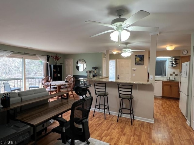 dining area featuring ceiling fan, light wood-style floors, and baseboards