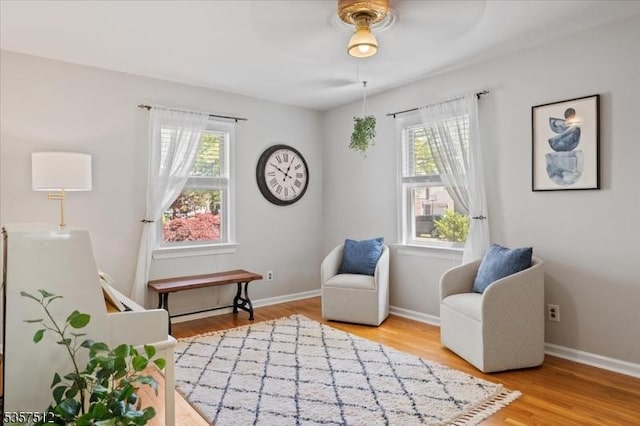 living area with healthy amount of natural light, wood finished floors, and baseboards
