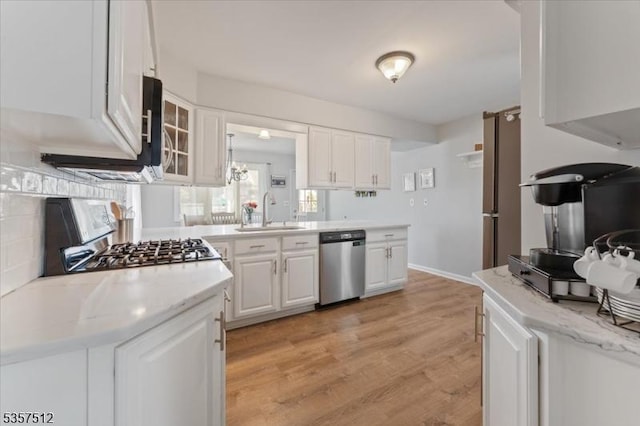 kitchen with stainless steel dishwasher, gas range oven, white cabinetry, a sink, and light wood finished floors