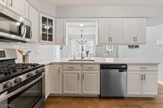 kitchen with appliances with stainless steel finishes, a sink, light countertops, a chandelier, and white cabinetry