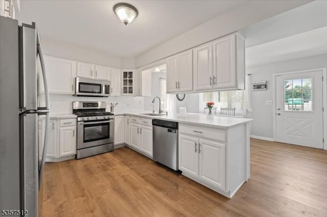 kitchen featuring stainless steel appliances, a sink, white cabinetry, and light wood finished floors